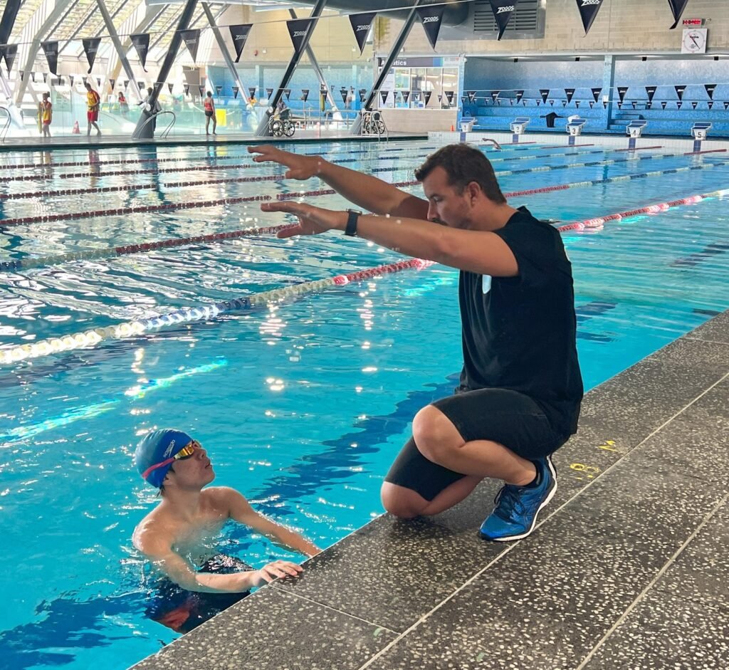 ason Cram mentoring a young swimmer poolside in Sydney